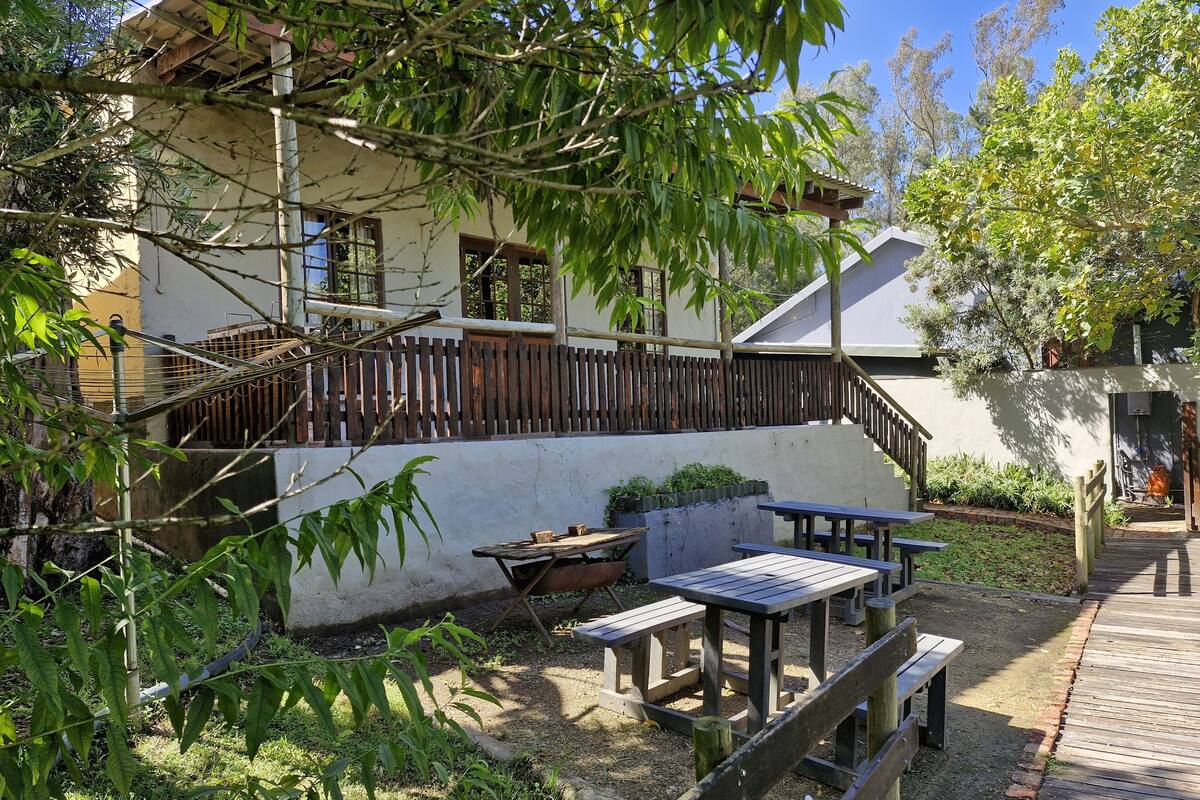 A courtyard with outdoor seating, a staircase, and a building with a wooden fence.