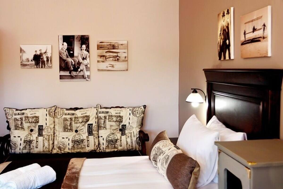 A hotel room with a bed, a nightstand, a lamp, and wall art.