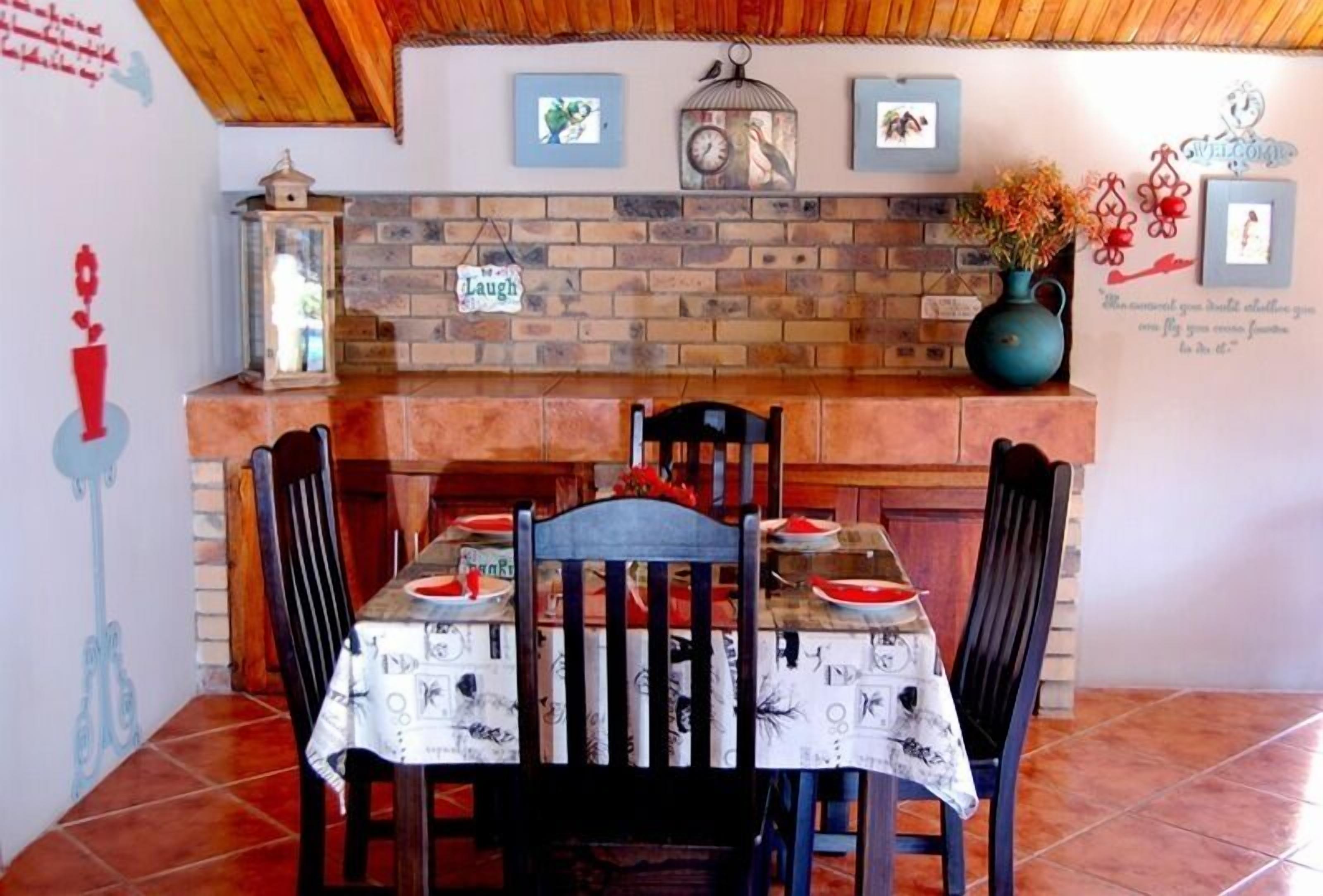 A dining area with a brick wall, wooden ceiling, and a table set with plates and a vase.