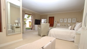 A hotel room with a bed, a chair, a desk, a television, and a large mirror. - Constantia Garden Suites (Cape Town)