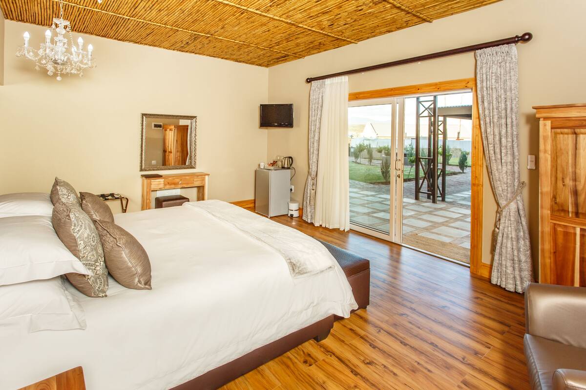 Une chambre dotée d’un grand lit, d’un plancher en bois, d’une télévision, d’un bureau et offrant une vue sur l’extérieur.