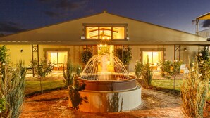 Une fontaine bien éclairée dans une cour, avec un bâtiment en arrière-plan.