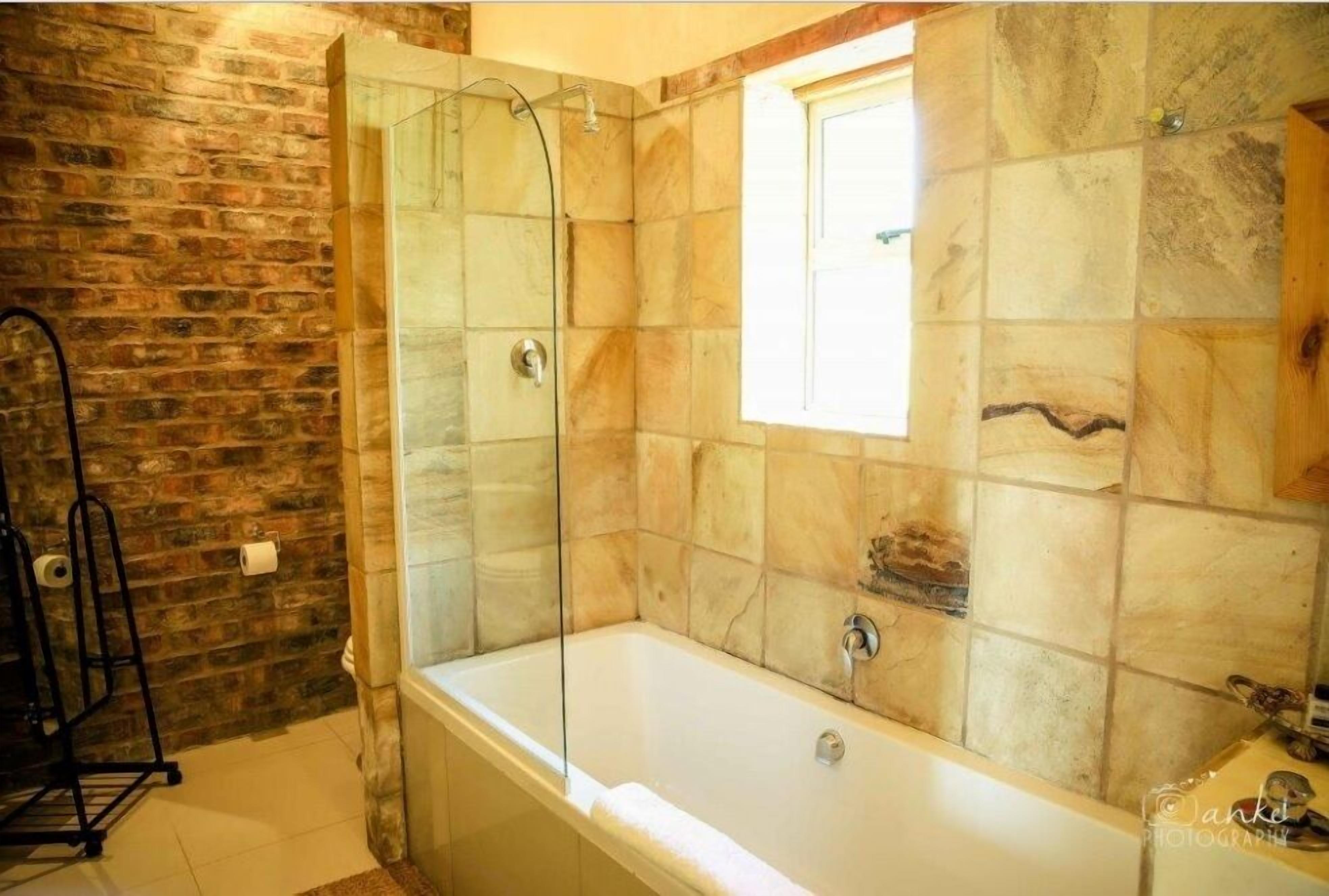 A bathroom with a glass-enclosed shower, a bathtub, and a window.