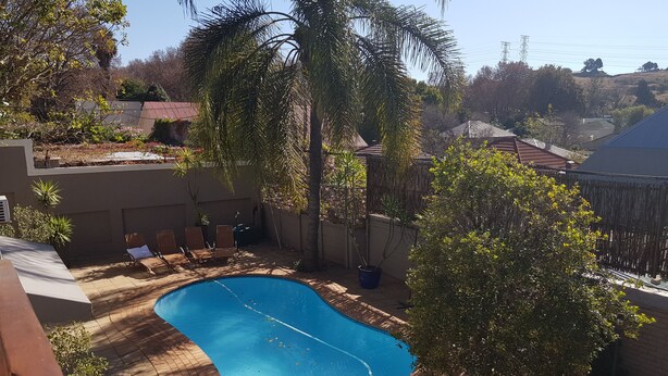 A swimming pool with a brick deck, surrounded by potted plants and a few lounge chairs. - Mi Casa Su Casa Boutique Accommodation (Johannesburg)