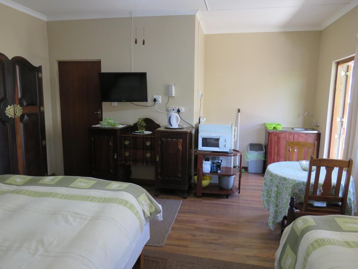 Una habitación con dos camas, televisión, microondas y una pequeña kitchenette.