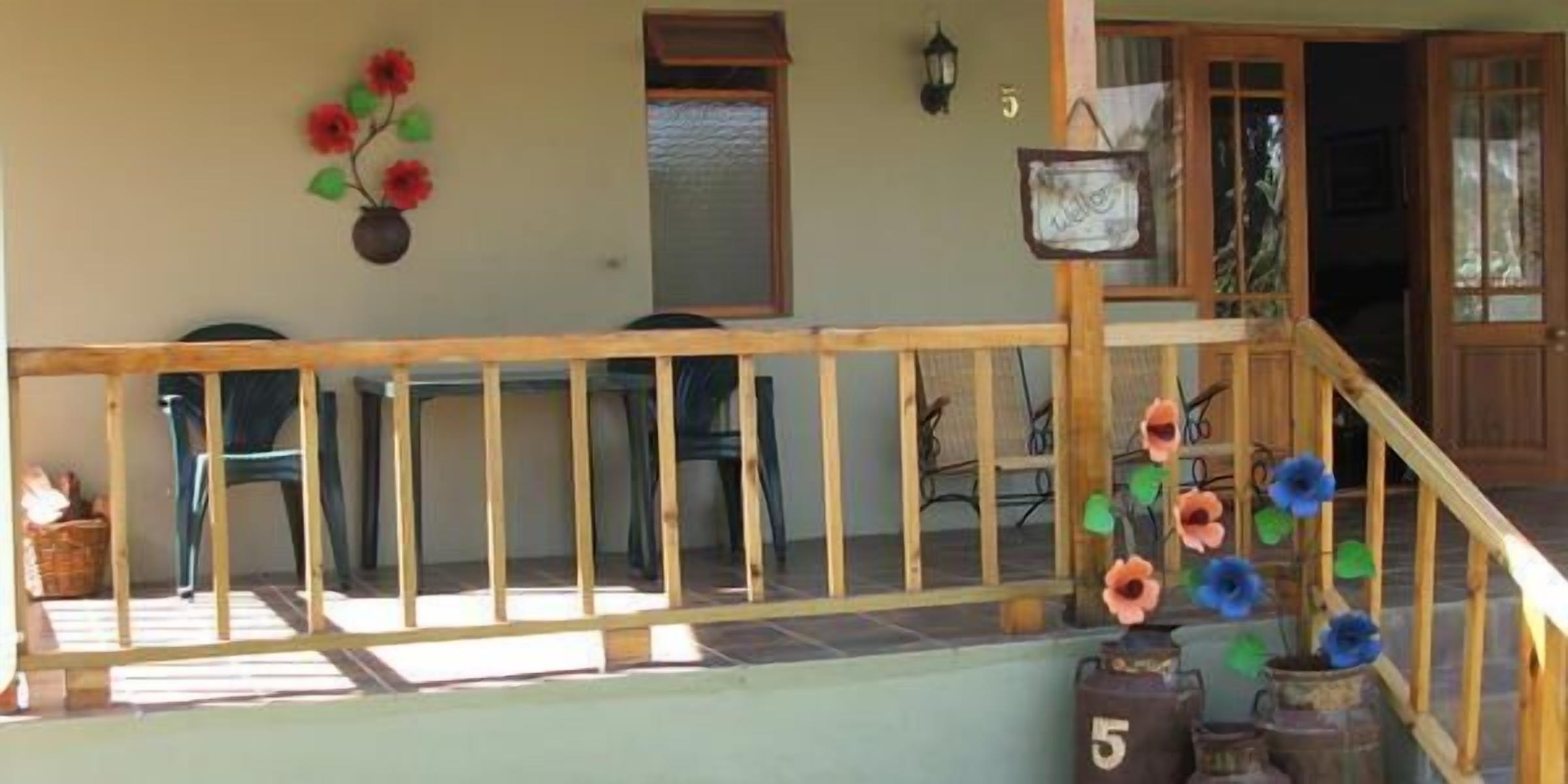 Un balcone in legno con ringhiera, un vaso con fiori e un cartello con il numero 5.
