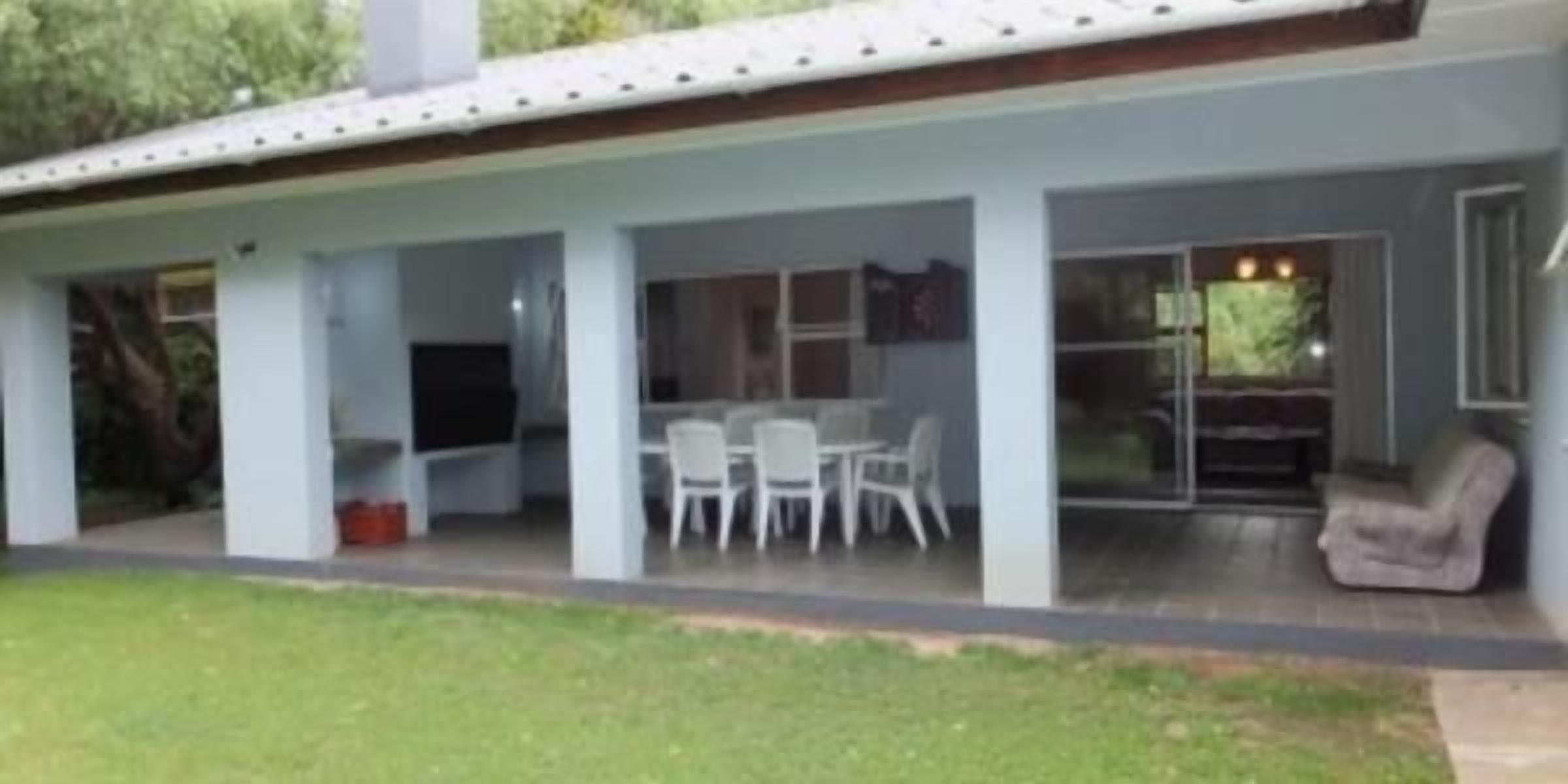 Una casa moderna con un patio cubierto, una mesa de comedor y sillas.