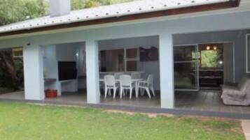 Una casa moderna con un patio cubierto, una mesa de comedor y sillas.
