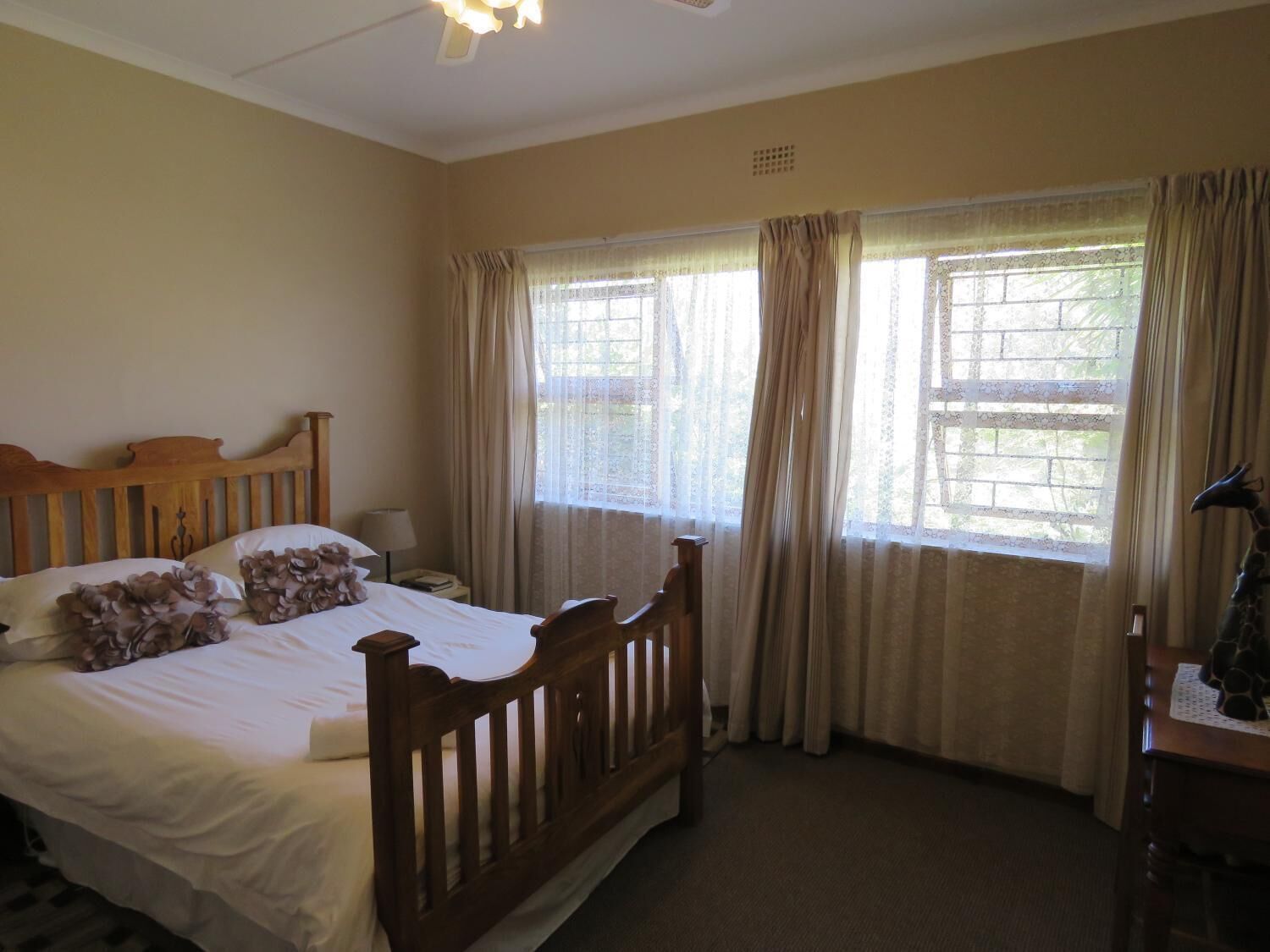 Un dormitorio con una cama de madera, una mesita de noche, un escritorio y una ventana con cortinas.