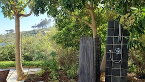 Ein Garten mit einer gefliesten Dusche, einer Bank und Blick auf eine hügelige Landschaft.