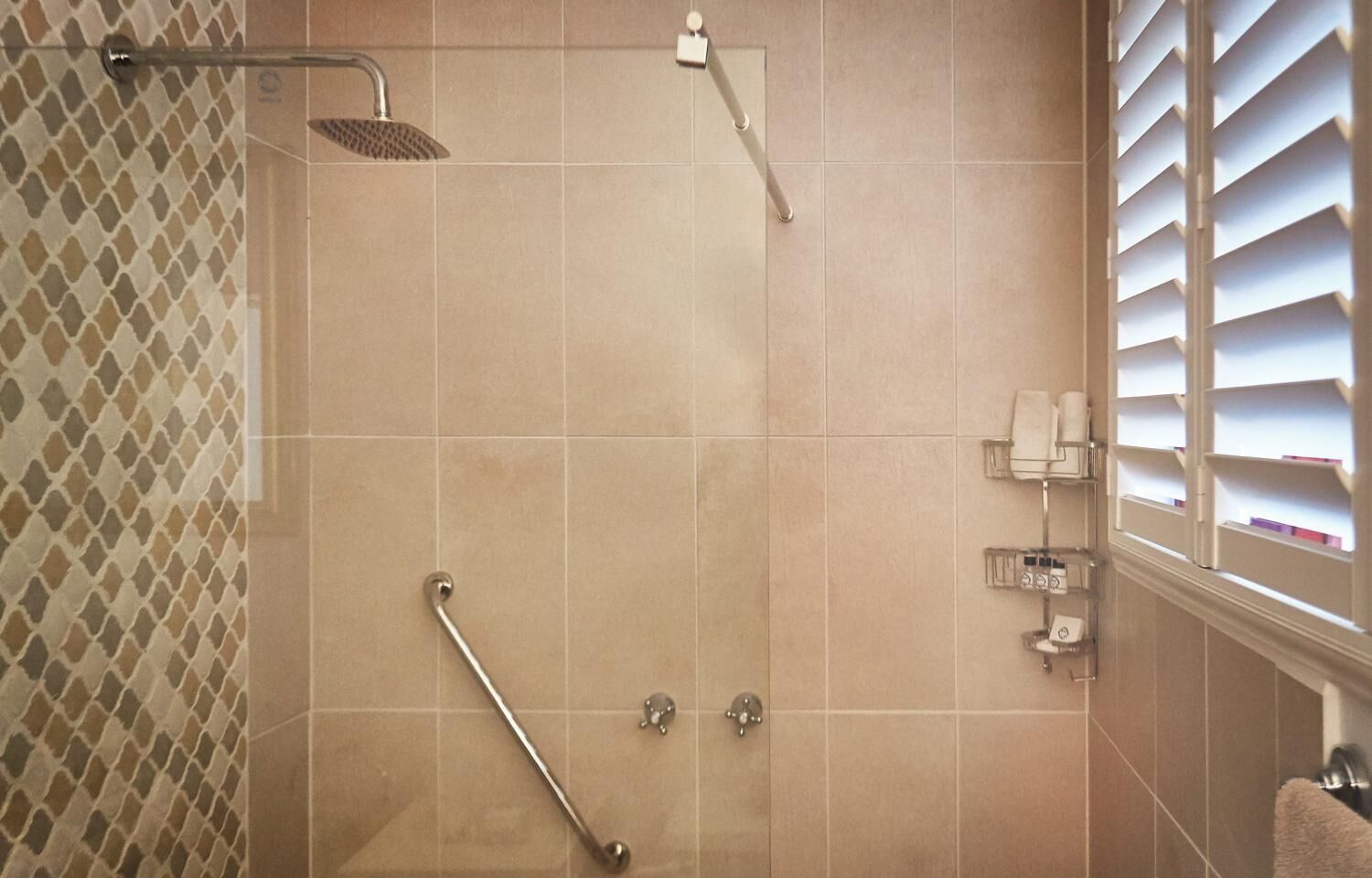 A shower with a handheld showerhead, a handheld showerhead, and a handheld showerhead.