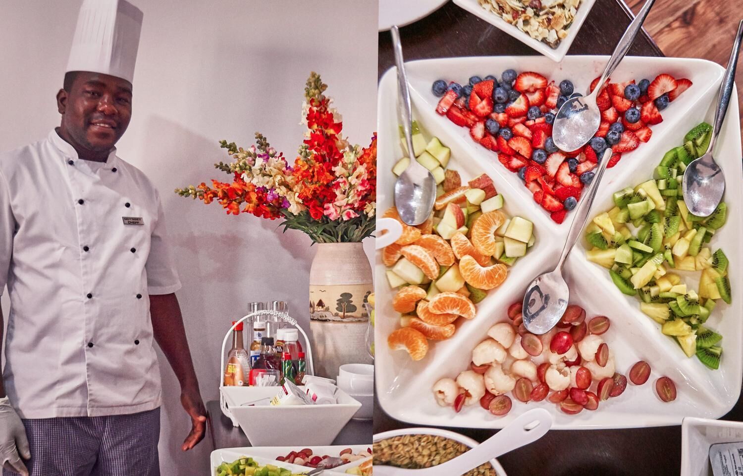 A chef standing next to a buffet with various fruits and a vase of flowers.