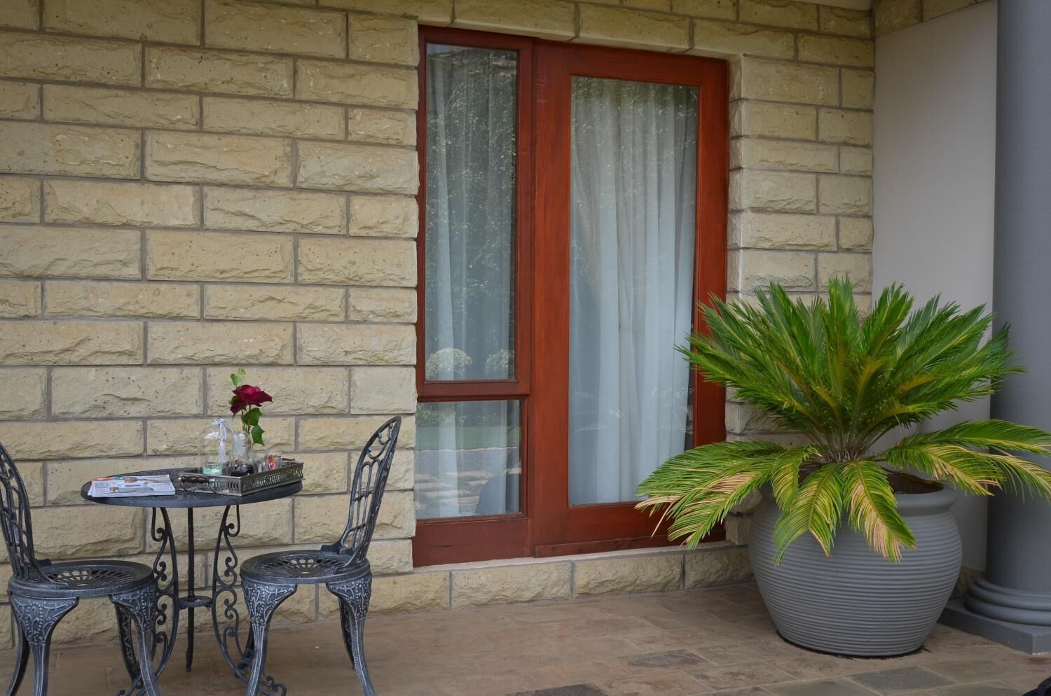 A stone wall with a wooden door and a large potted plant.
