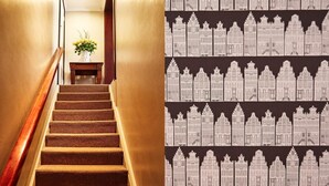 A staircase with a wooden handrail and carpeted steps leading to a room with a vase of flowers. - Riverwalk B and B (Clarens)