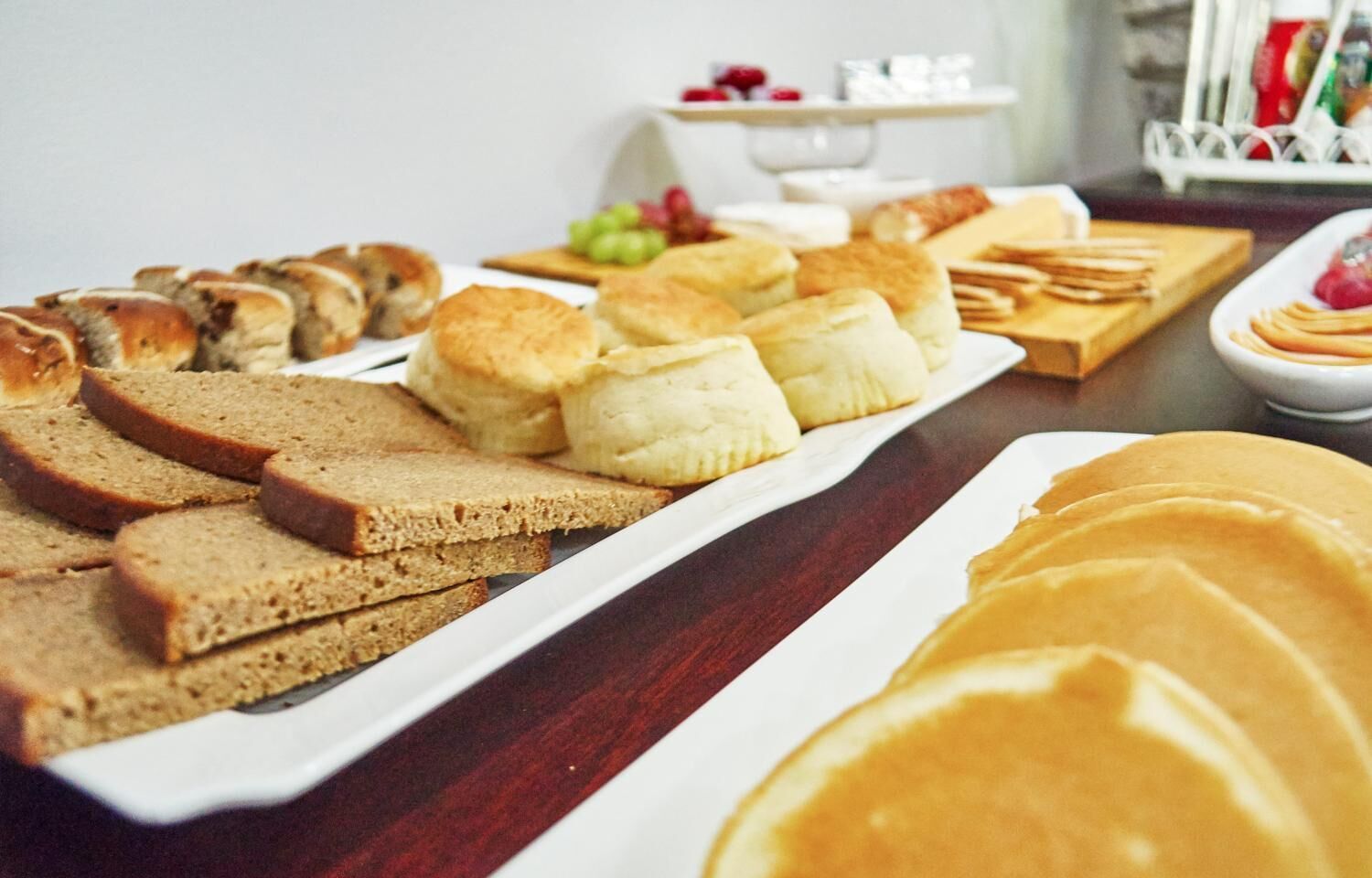 A breakfast buffet with various breads, pastries, and fruits.