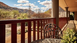 A balcony with a view of a mountainous landscape, a table with a chair, and a covered area with columns. - Riverwalk B and B (Clarens)