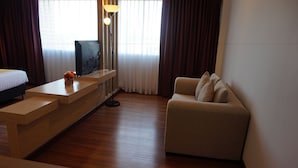 Una habitación de hotel moderna con un escritorio de madera, un sofá y un televisor.