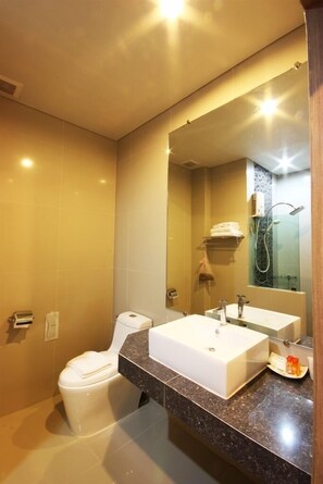 Une salle de bain moderne avec un grand miroir, un lavabo blanc et une douche.