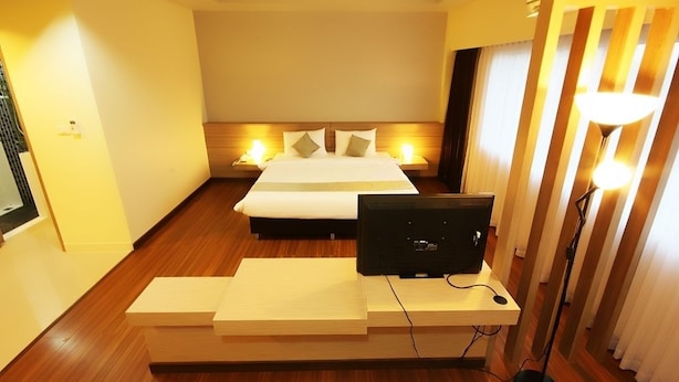 Una habitación de hotel con una cama, lámparas de noche, un escritorio con computadora y televisión.