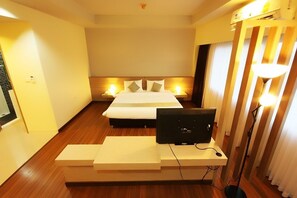 A hotel room with a bed, bedside lamps, a desk with a computer, and a TV. - Akelada Hotel (Nang Rong)