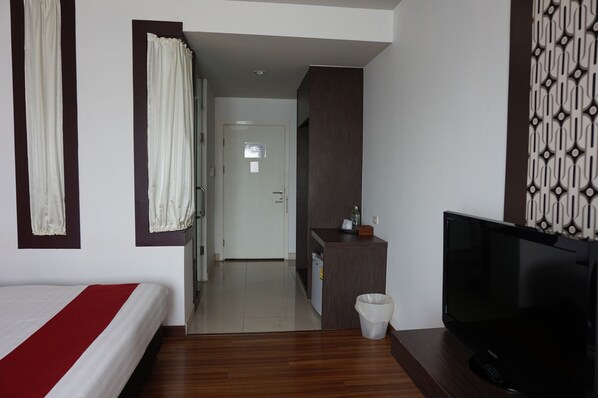 A hotel room with a bed, a TV, a small kitchenette, and a bathroom visible through an open door.