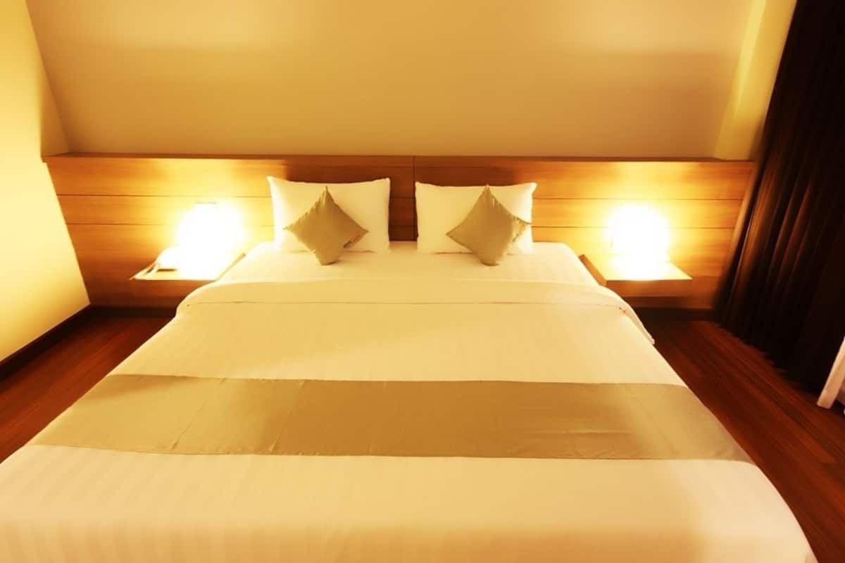 A hotel room with a large bed, wooden headboard, and two bedside lamps.