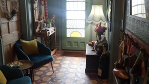 A cozy room with a blue sofa, a patterned floor, a green door with a window, and a wall-mounted lamp. - Newberry Beach Lodge (Ilfracombe)