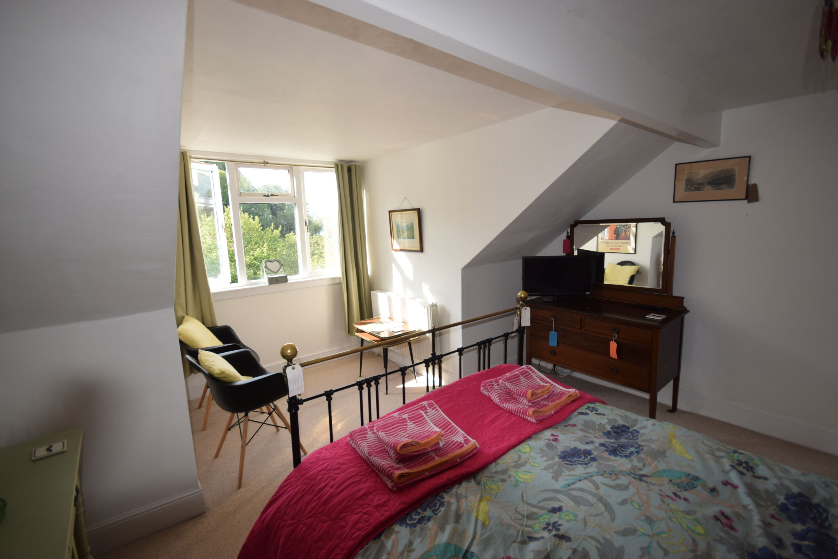 A bedroom with a bed, a desk, a chair, and a dresser.