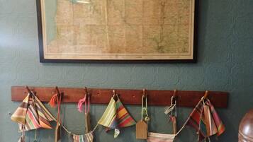 A framed map on the wall, a radiator below, and a rack with various bags and a boot.
