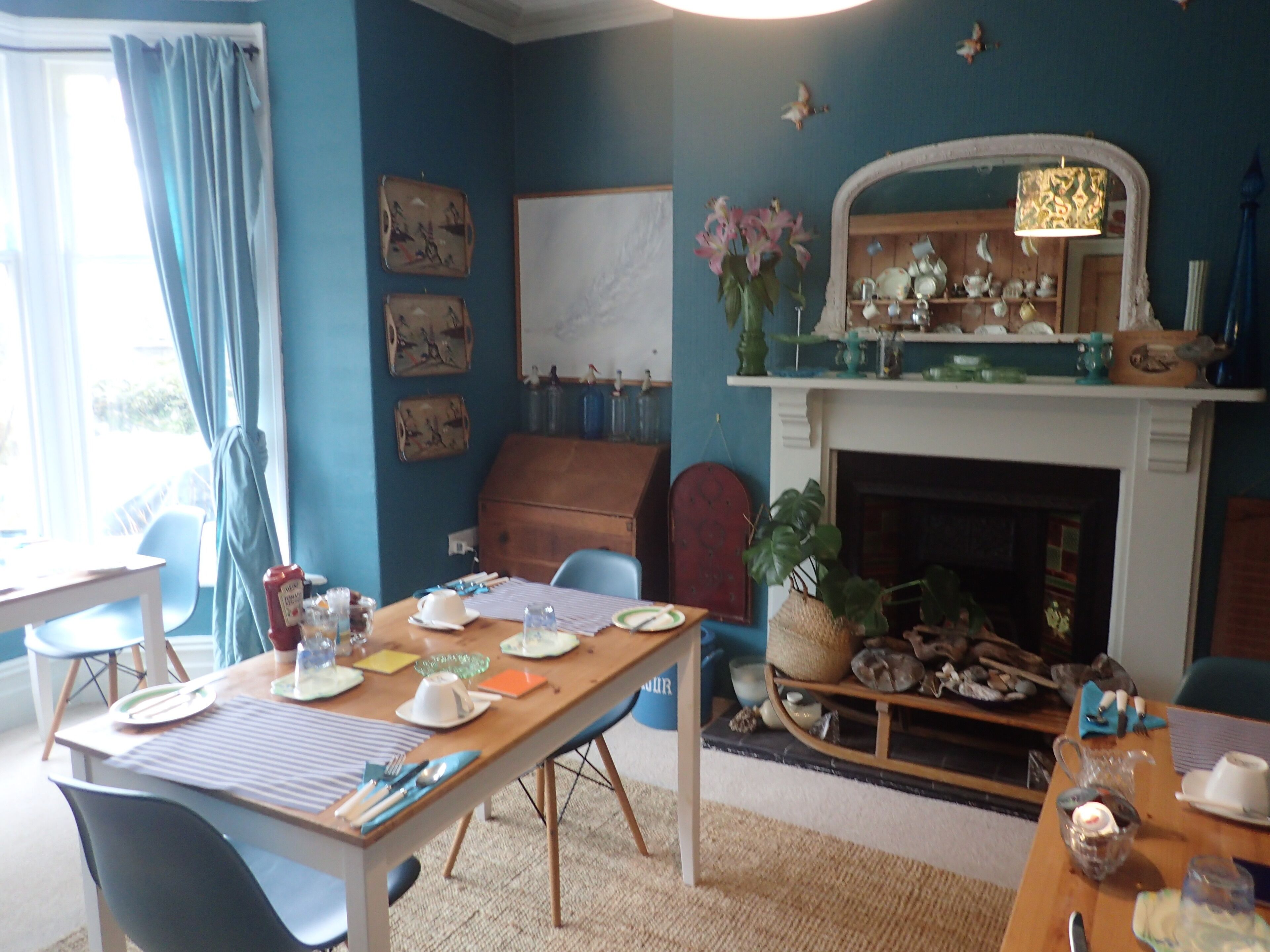 A dining area with a wooden table set for four, chairs, a fireplace, and wall decorations.