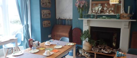 A dining area with a wooden table set for four, chairs, a fireplace, and wall decorations.