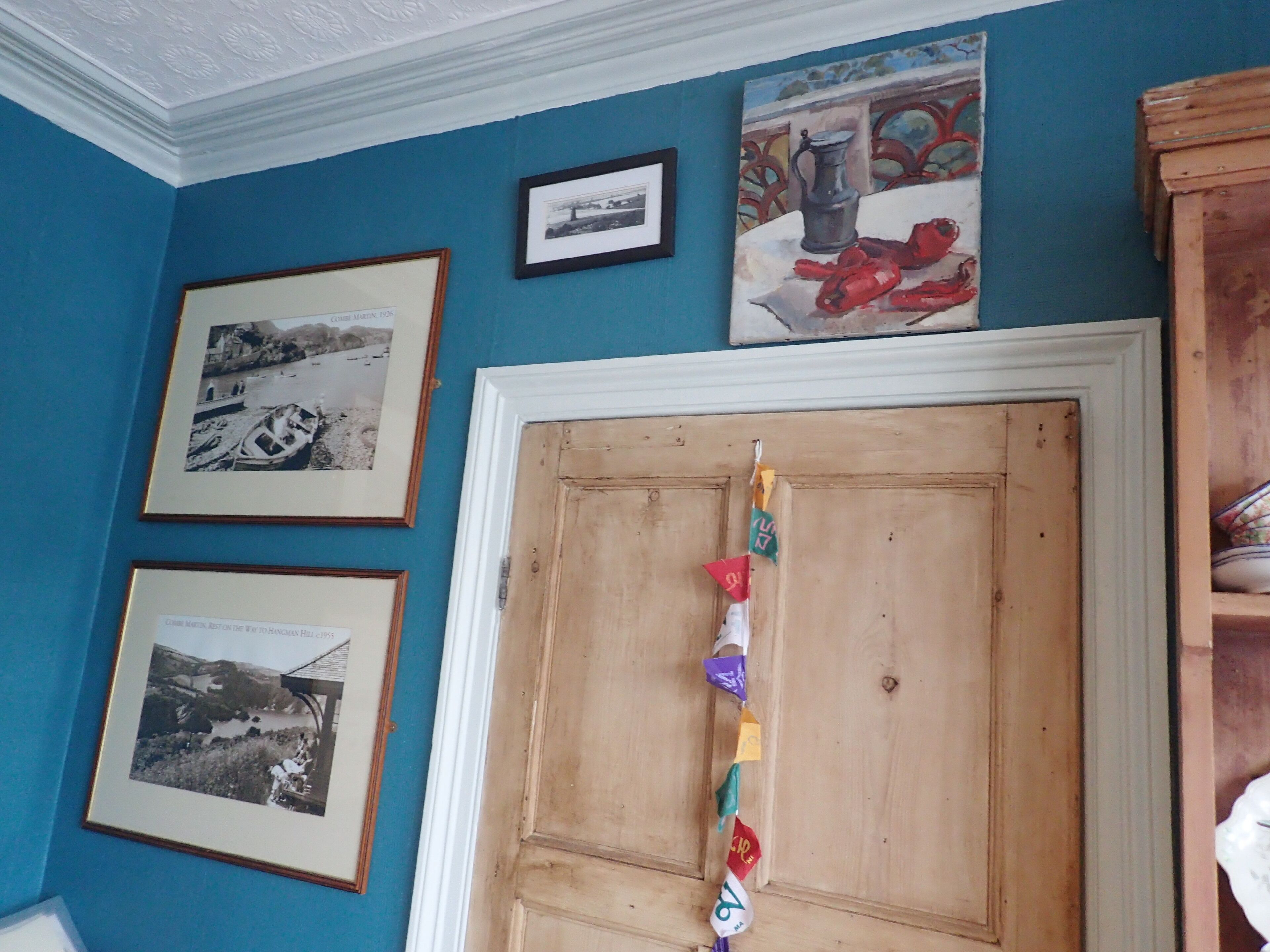 Une pièce aux murs bleus, avec une porte en bois et des photographies encadrées.
