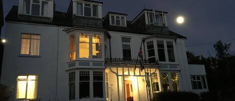 A two-story building with multiple windows, a balcony with railings, and a flag.