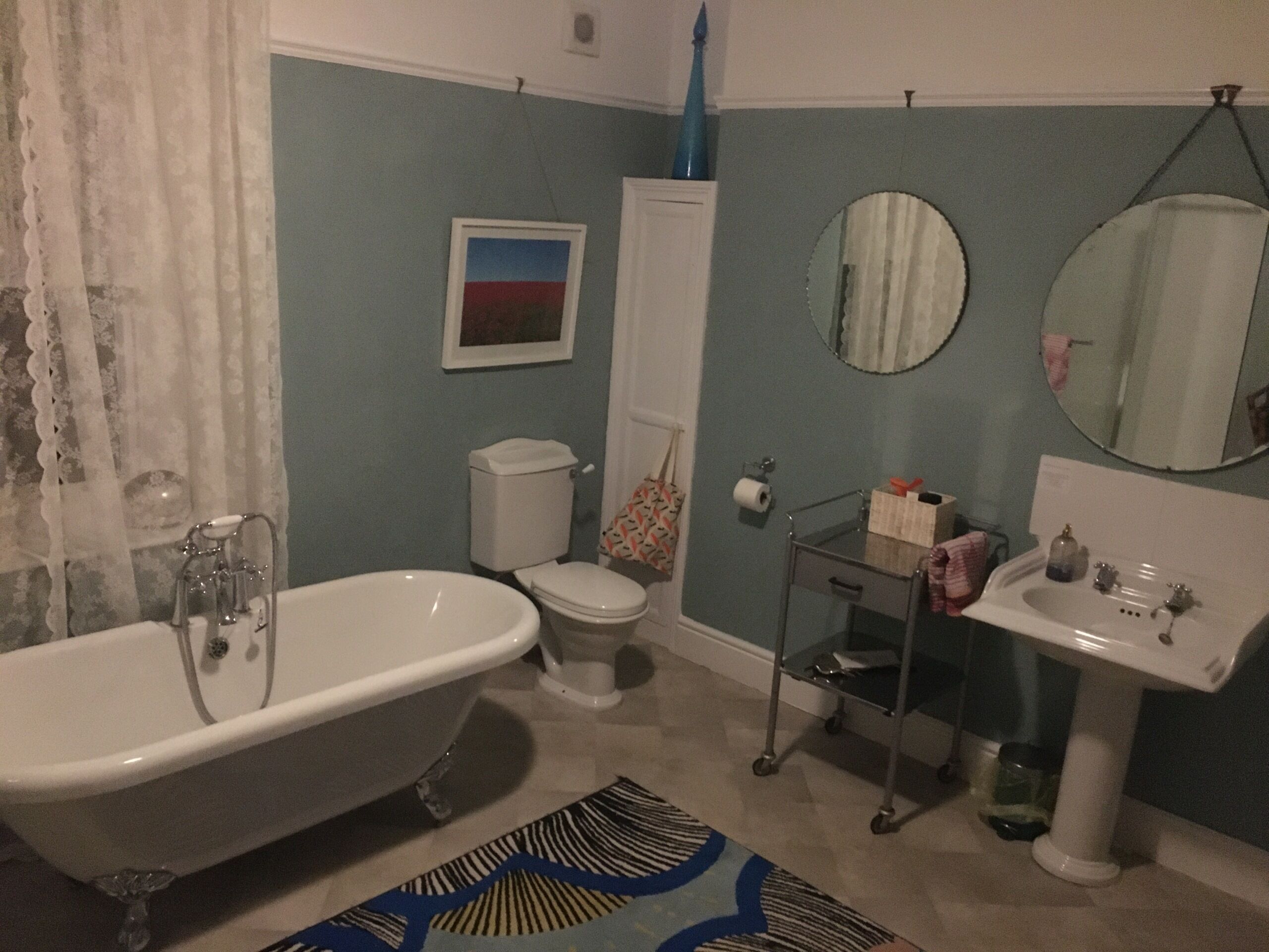 A bathroom with a bathtub, toilet, sink, and mirrors.