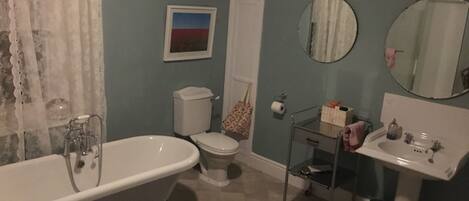 A bathroom with a bathtub, toilet, sink, and mirrors.