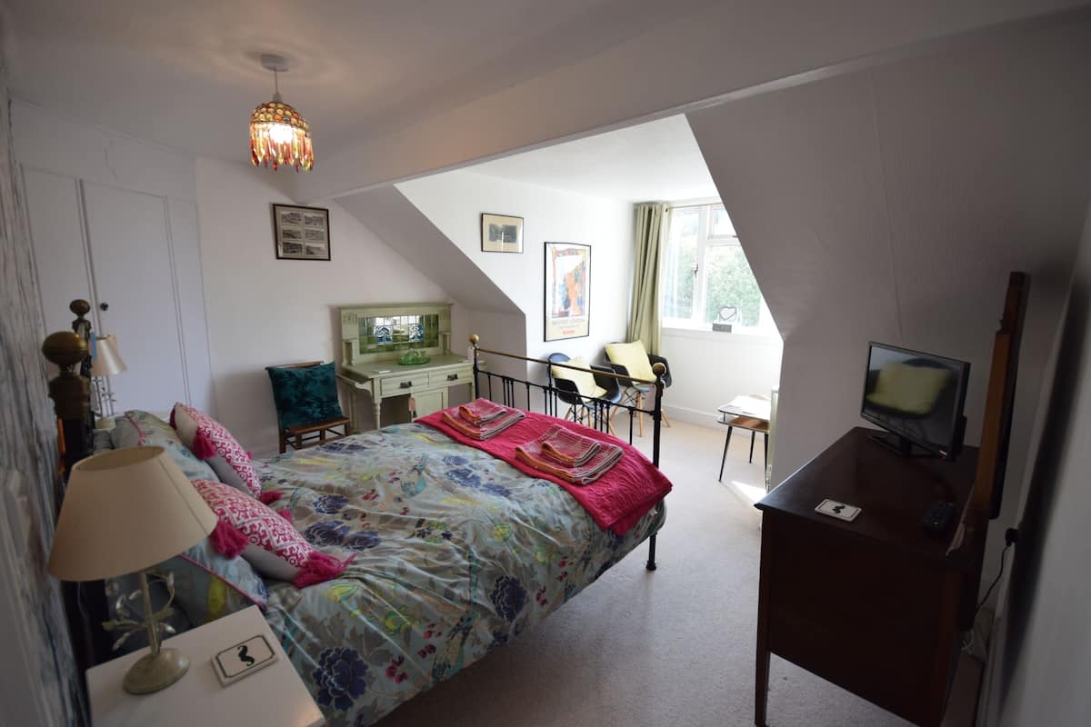 Une chambre à coucher comprenant un lit, un bureau, une chaise, une télévision et une petite table.