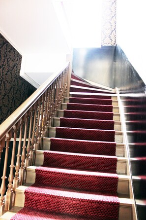A staircase with a red carpet and wooden balusters.
