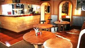 A cozy restaurant interior with wooden furniture, a bar area, and a chalkboard menu. - Lumsden Hotel (Lumsden)