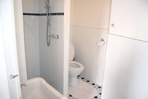 A bathroom with a bathtub, toilet, and shower.