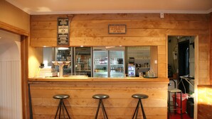 A bar area with wooden walls, a glass display case, and three stools. - Lumsden Hotel (Lumsden)