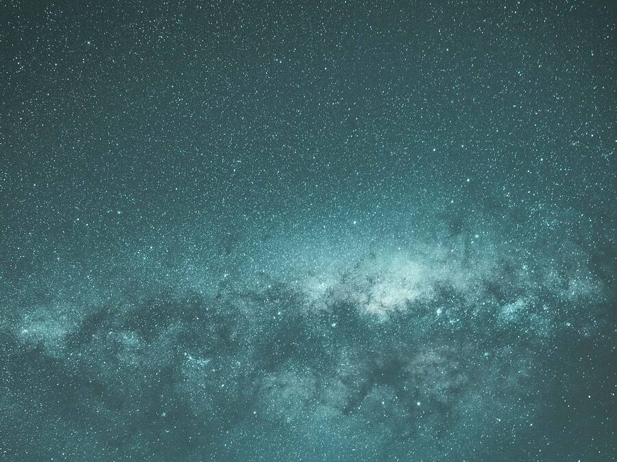 Céu noturno repleto de estrelas e da Via Láctea.