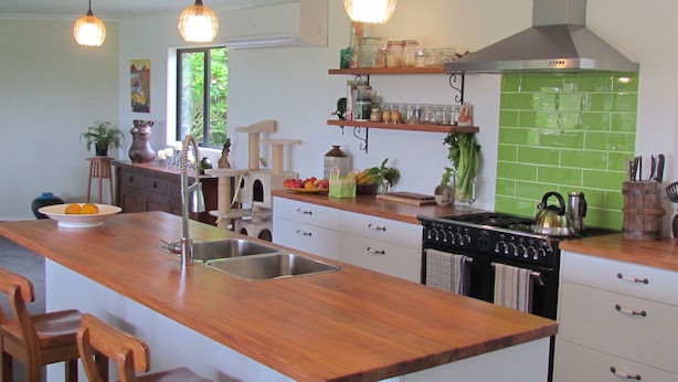 A kitchen with a wooden island, stainless steel appliances, and a green tiled backsplash. - Rolling Hills Country Stay B&B (Oropi)