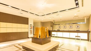 A hotel lobby with a reception desk, seating area, and a decorative plant centerpiece. - Hotel IL Cuore Namba (Osaka)