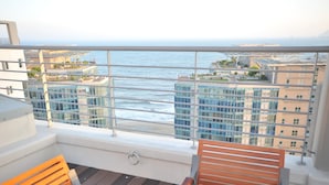 A balcony with a view of the ocean and buildings. There are wooden chairs and a table. - Hotel The Mark Haeundae (Busan)