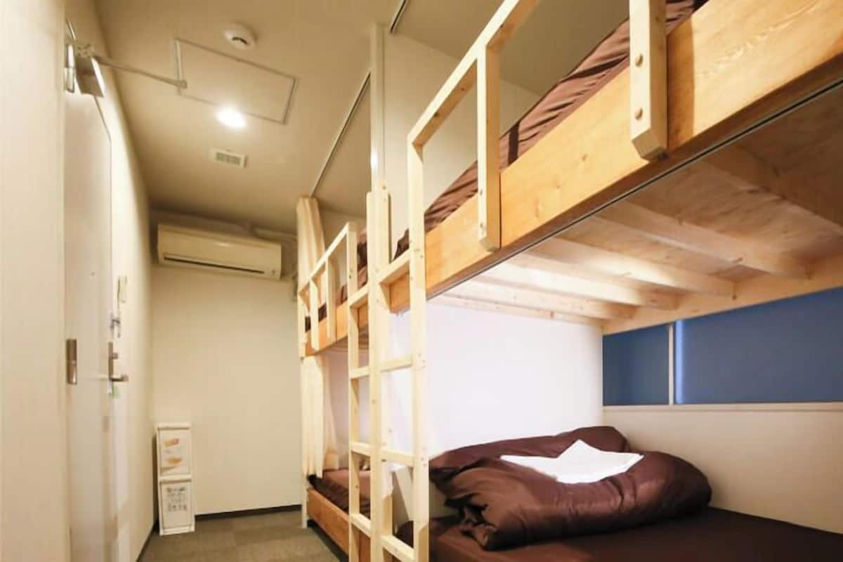 Dormitorio con literas, ventana, puerta y unidad de aire acondicionado.