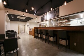A modern bar area with a wooden counter, bar stools, and a menu board.