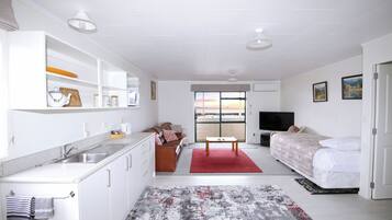 A modern, well-lit room with a kitchenette, a dining area, and a bed.