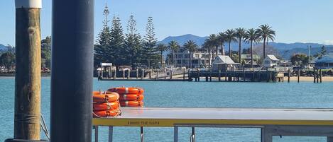 A waterfront view with a pier, lifebuoys, and a building with a mountain backdrop.