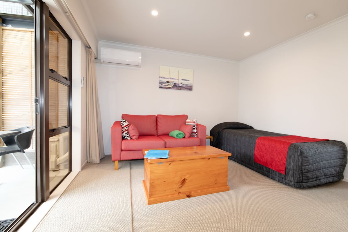 A compact living space with a sofa, a small wooden table, and a futon bed.