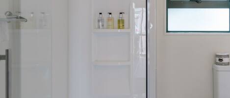 Un baño moderno con cabina de ducha de vidrio, inodoro y ventana.